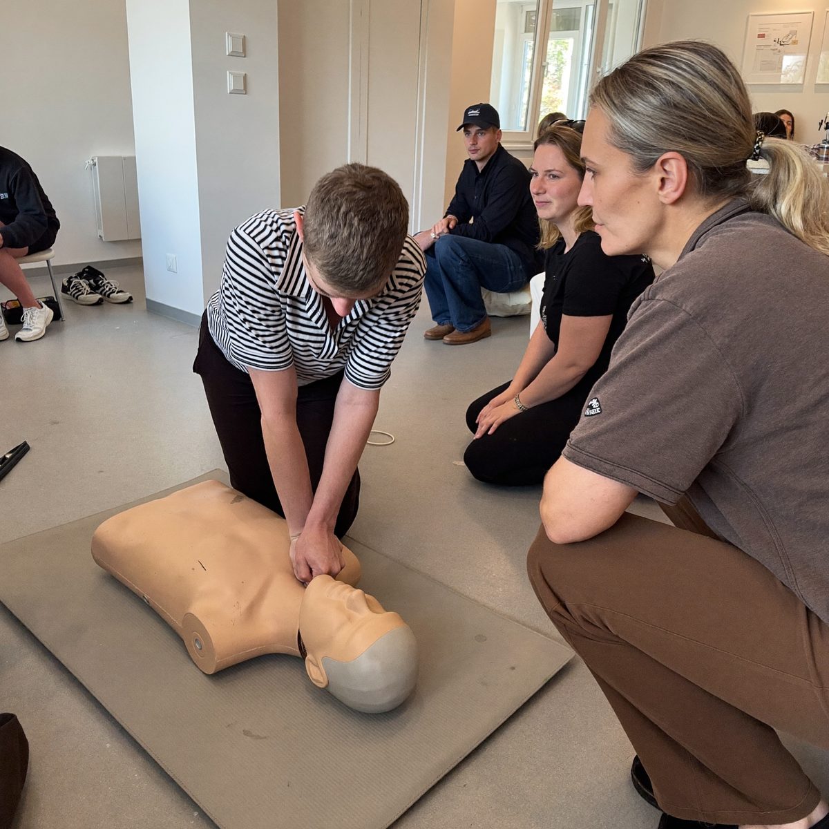 Instruktør viser hjertemassage på øvelsesdukke